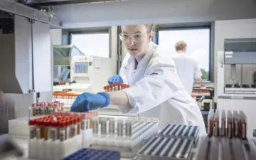 Foto van een laboratoriummedewerker die een buisje bloed uit de kast pakt