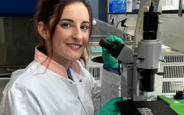 Foto van onderzoeker Despoina Trasanidou bij een microscoop