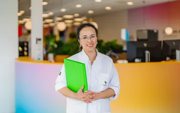 Staande donorarts met een map in haar hand lacht vriendelijk in de camera