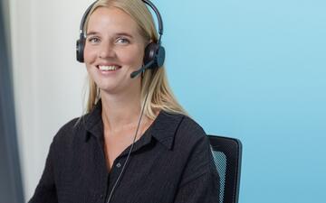 Sanquin-collega met headset achter een computer