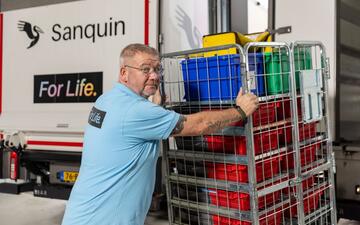 Chauffeur laadt draadkar met bloedproducten op een Sanquin vrachtwagen