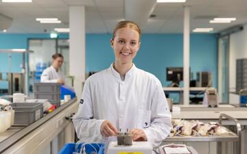 Vrouw in Sanquin labjas staat bij een apparaat voor bloedbewerking