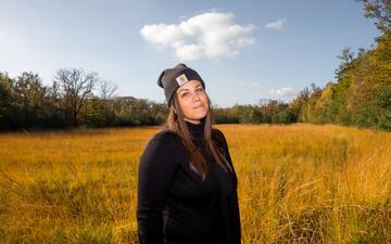 Portretfoto van Sara  bij een grasveld en bomen op de achtergrond