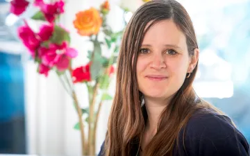 portretfoto van donor Marielle mmet een vaas rode en oranje rozen op de achtergrond