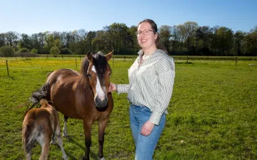 Foto van donor Rianne in een veld met twee pony's. 