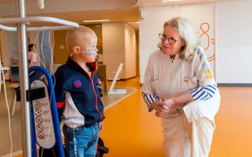 Foto van kinderoncoloog Lieve Tytgat en een jonge patient in de ziekenhuisgang