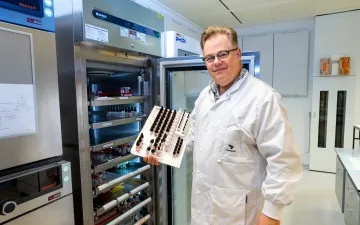 Foto van bloedgroepenexpert Peter Ligthart in labjas voor een kast met bloedmonsters