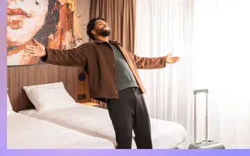 Gast laat zich ontspannen achterover vallen op het bed in een hotelkamer met twee bedden
