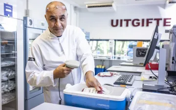 Foto van een Sanquinmedewerker in labjas die bloedproducten klaar maakt voor uitgifte naar de ziekenhuizen