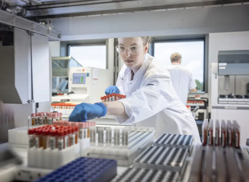 Foto van een laboratoriummedewerker die een buisje bloed uit de kast pakt