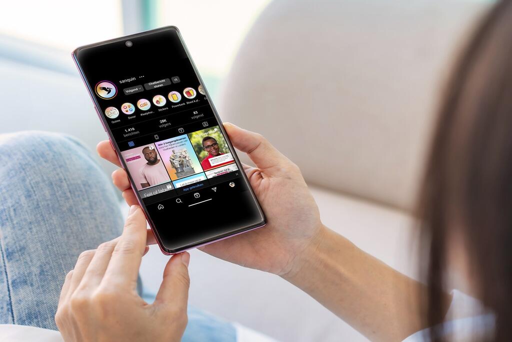 Foto van persoon met een mobiele telefoon in de hand. Op het scherm staat Sanquins instagram-account.