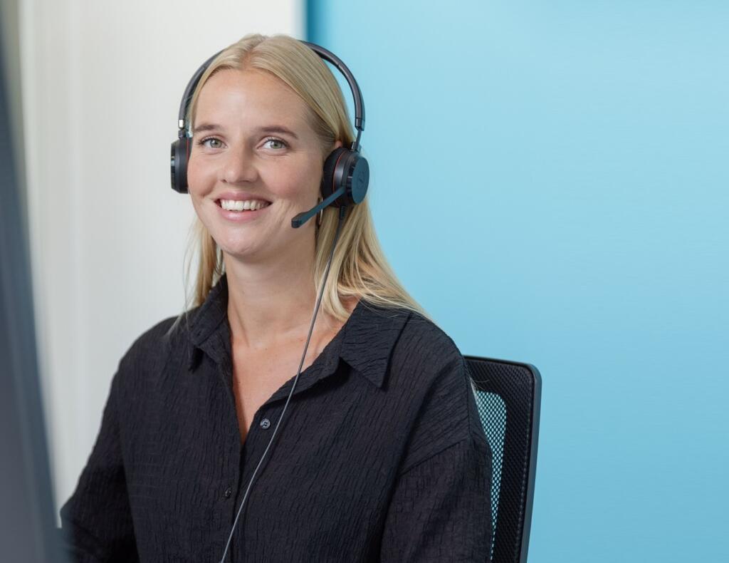 Sanquin-collega met headset achter een computer