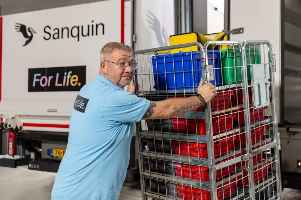 Chauffeur laadt draadkar met bloedproducten op een Sanquin vrachtwagen