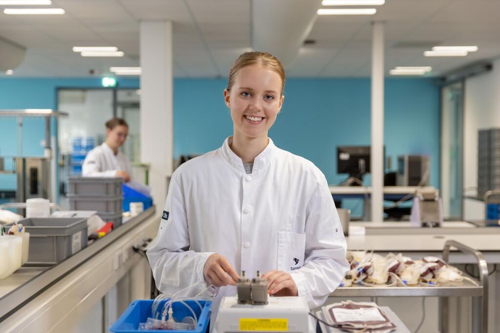 Vrouw in Sanquin labjas staat bij een apparaat voor bloedbewerking