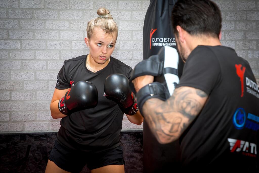 Vrouw met bokshandschoenen aan in een trainingsruimte