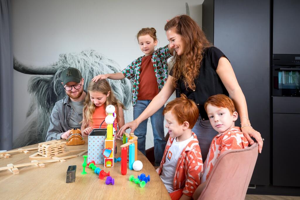 Foto van een gezin dat met speelgoed speelt aan de eettafel