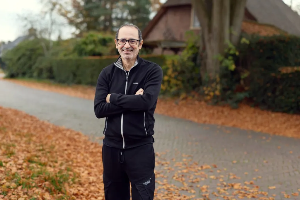 Foto van Orhan in een brede straat met herstbladeren