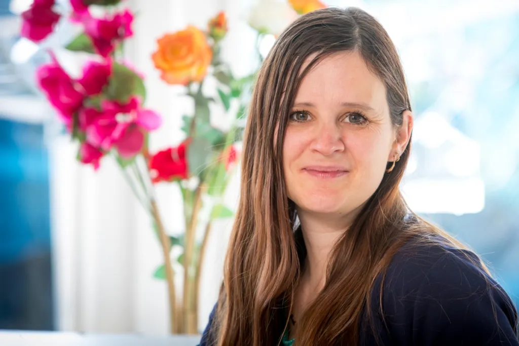 portretfoto van donor Marielle mmet een vaas rode en oranje rozen op de achtergrond