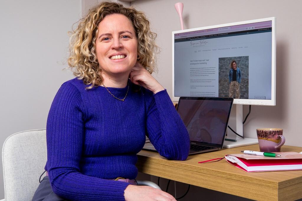 Foto van susan achter haar bureau. Het computerscherm toont haar bedrijfspagina. 