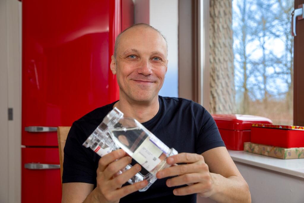 Foto van Rogier in de keuken met twee flesjes medicatie tegen CVID