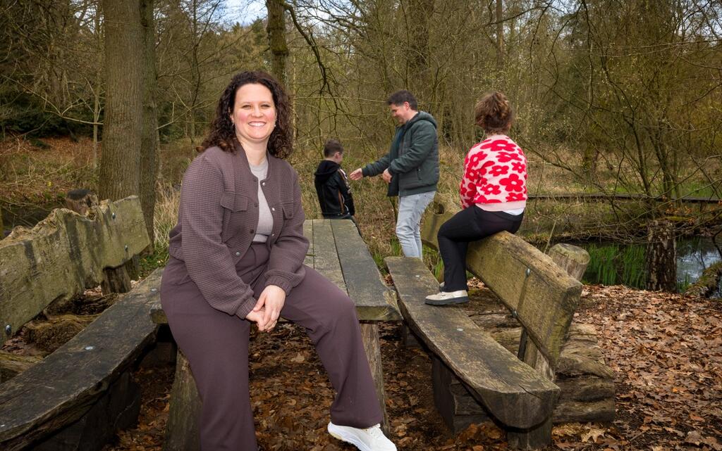 Foto van Senna, haar man en twee kinderen bij een bankje in het bos. 