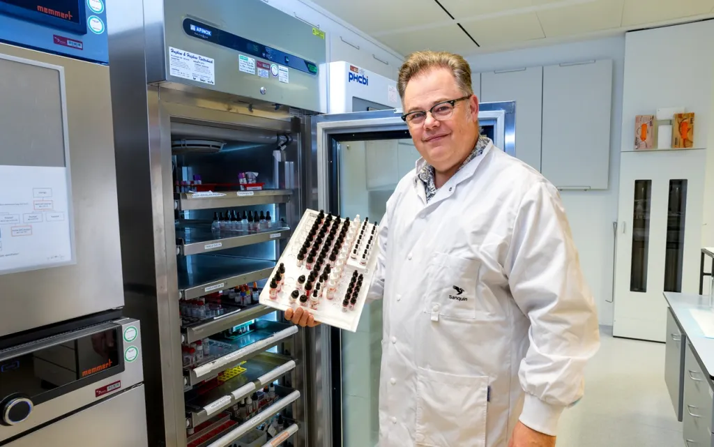 Foto van bloedgroepenexpert Peter Ligthart in labjas voor een kast met bloedmonsters