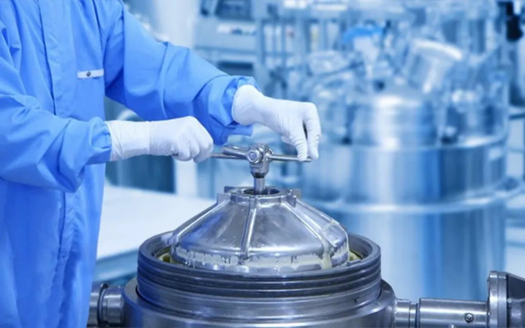 Detailfoto van de handen van een medewerker die draait aan de sluiting van een tank met plasma.  