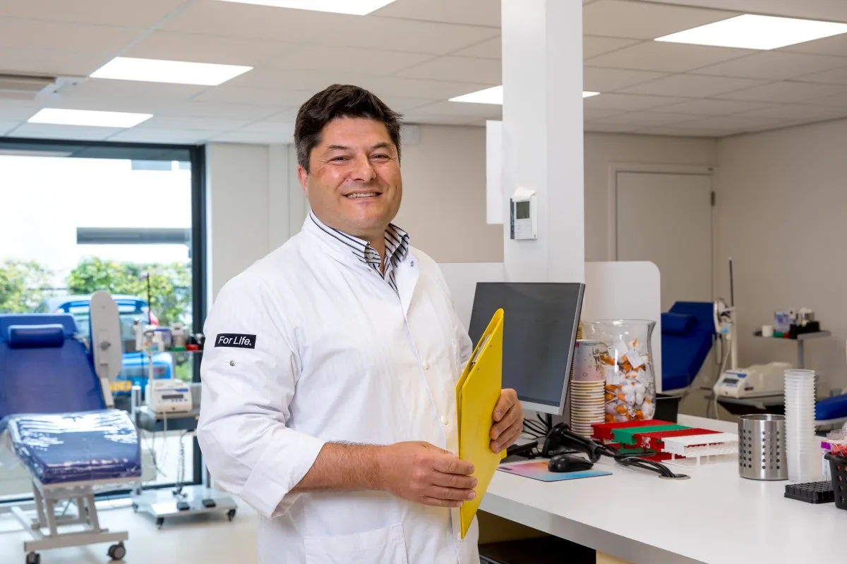 Donor-arts kijkt vriendelijk in de lens op een Sanquin locatie