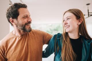 Glimlachende man en vrouw die gearmd in een woonkamer staan